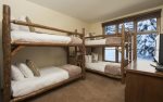 3rd bedroom with two sets of twin bunk beds, a flat screen TV, and an en-suite bathroom.